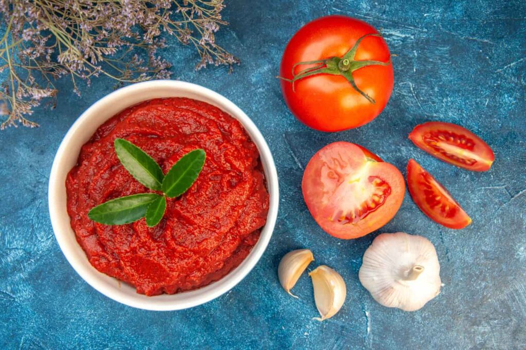 Cuenco de tomate frito, tomate partido y dientes de ajo